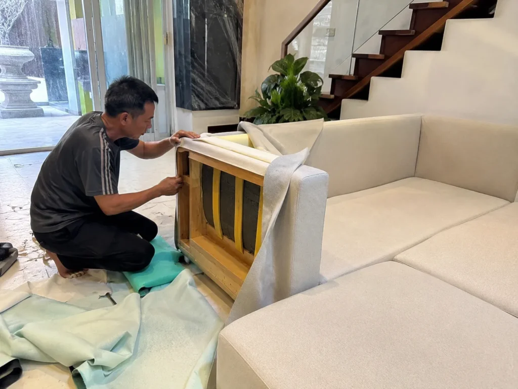 Thợ của xưởng bọc ghế sofa đang thi công bọc lại sofa tại nhà khách hàng với quy trình chuyên nghiệp và tỉ mỉ.
